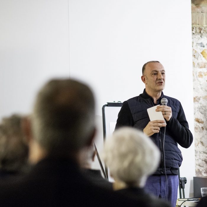 Our Artistic Director Dinos Aristidou with a microphone in one hand and cue cards in another speaking at our project launch.