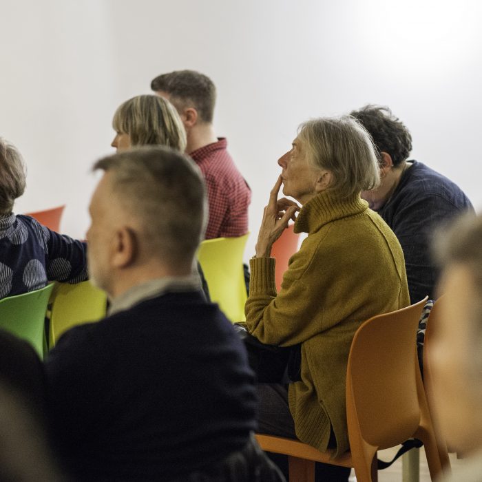 The audience at our project launch focusing on one person looking contemplative with their finger resting on their mouth.